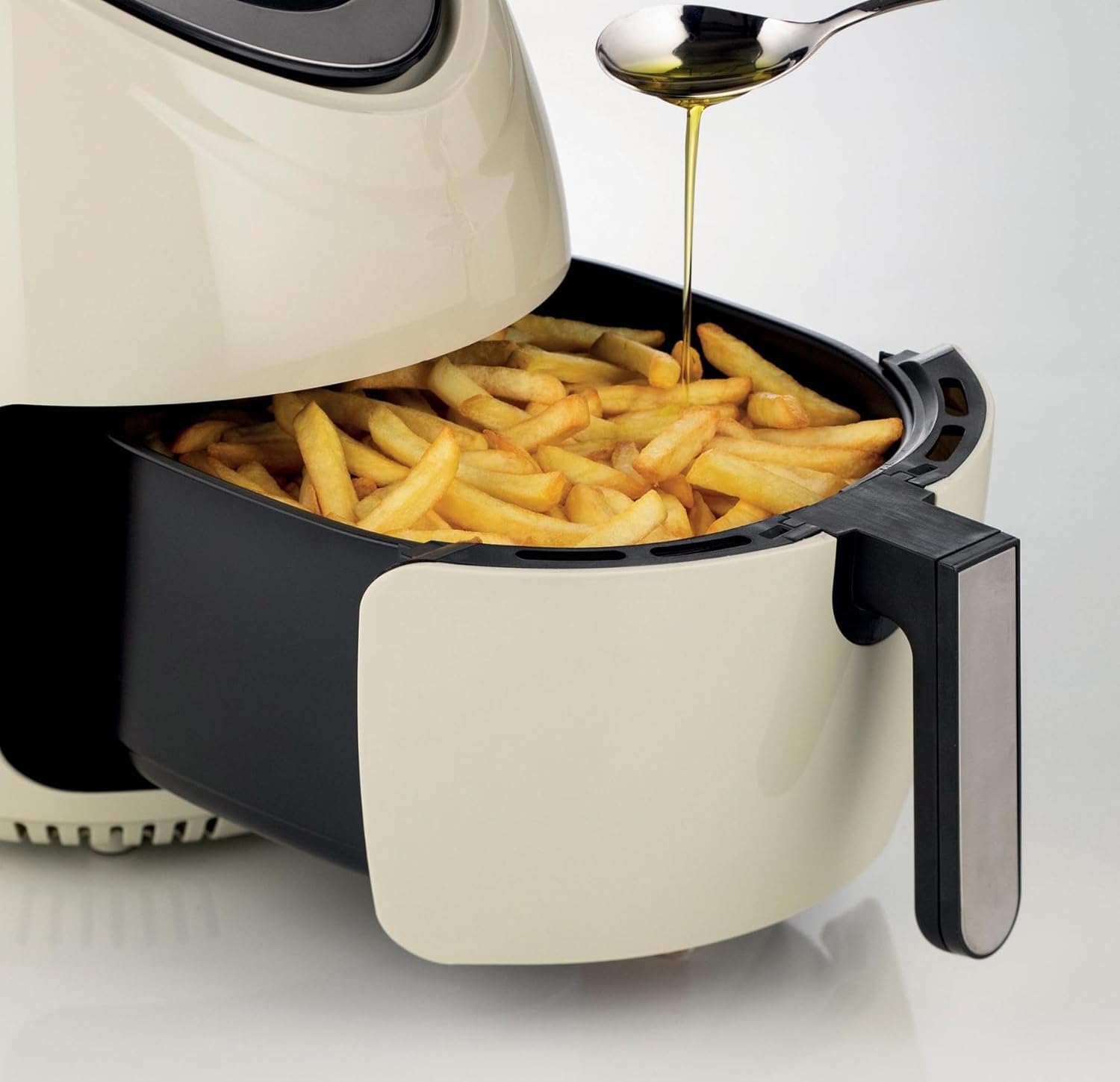 Panier de l'Ariete Airy Fryer XXL 4618 sorti de l'appareil, rempli de frites dorées, avec une cuillère d'huile versée au-dessus