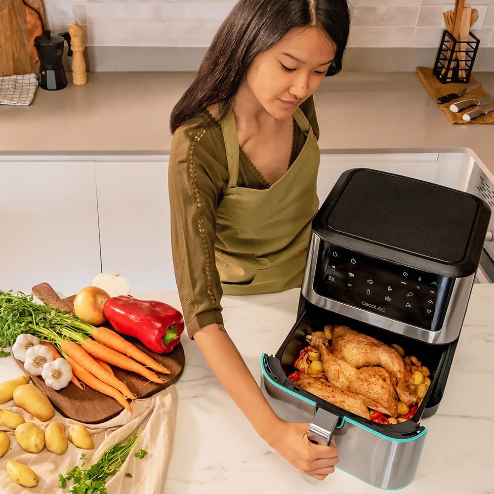 Tiroir du Cecotec Cecofry Supreme 8000 sorti sur un poulet entier ouvert entouré de pommes de terre et de poivrons, dans une cuisine claire