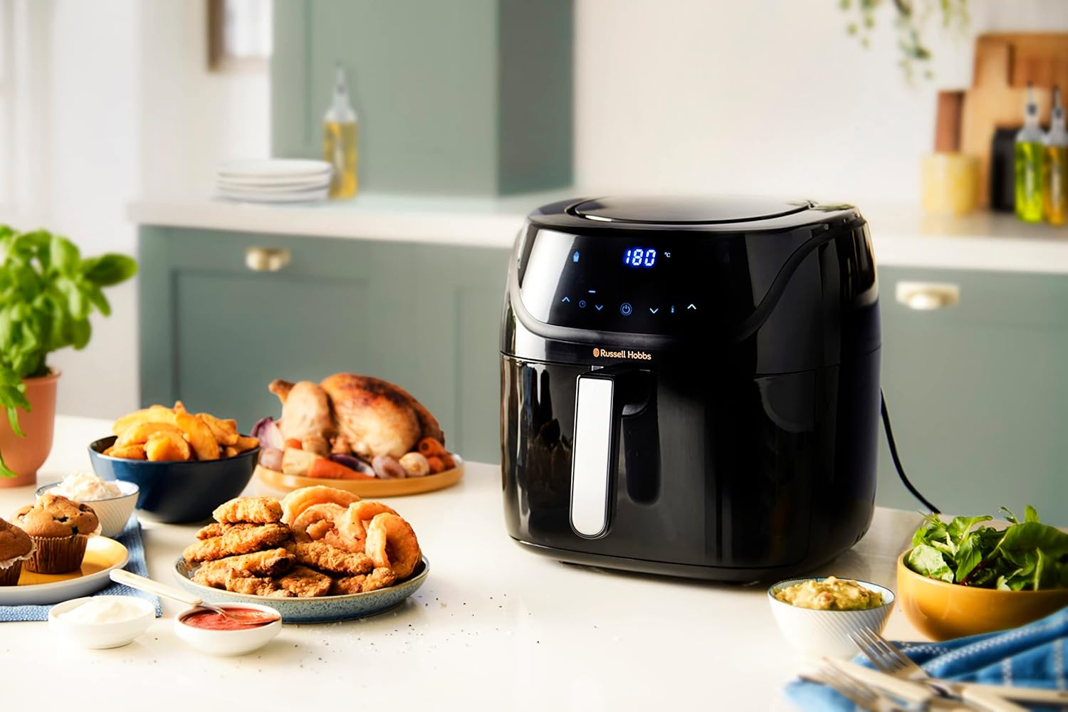 Russell Hobbs SatisFry 27160-56 fermé sur un plan de travail de cuisine, son format bas et large visible à côté de plats de nuggets, de muffins et de salade