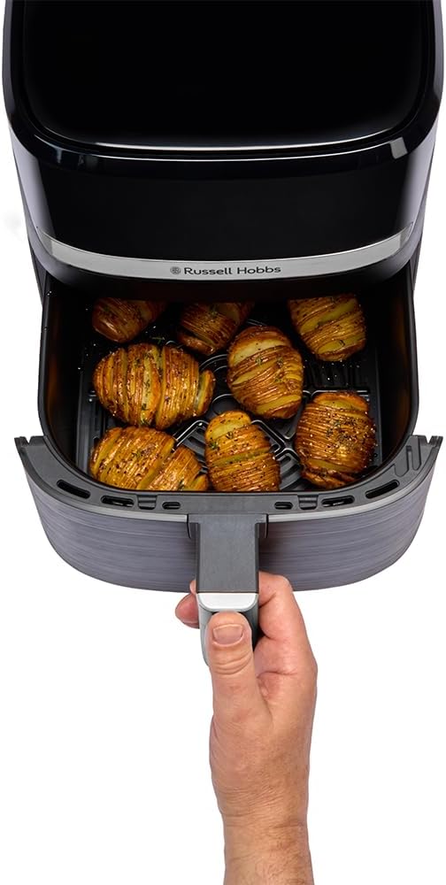 Panier du Russell Hobbs SatisFry Air 27621-56 tenu à la main, rempli de pommes de terre hasselback dorées posées sur la plaque de croustillance ajourée