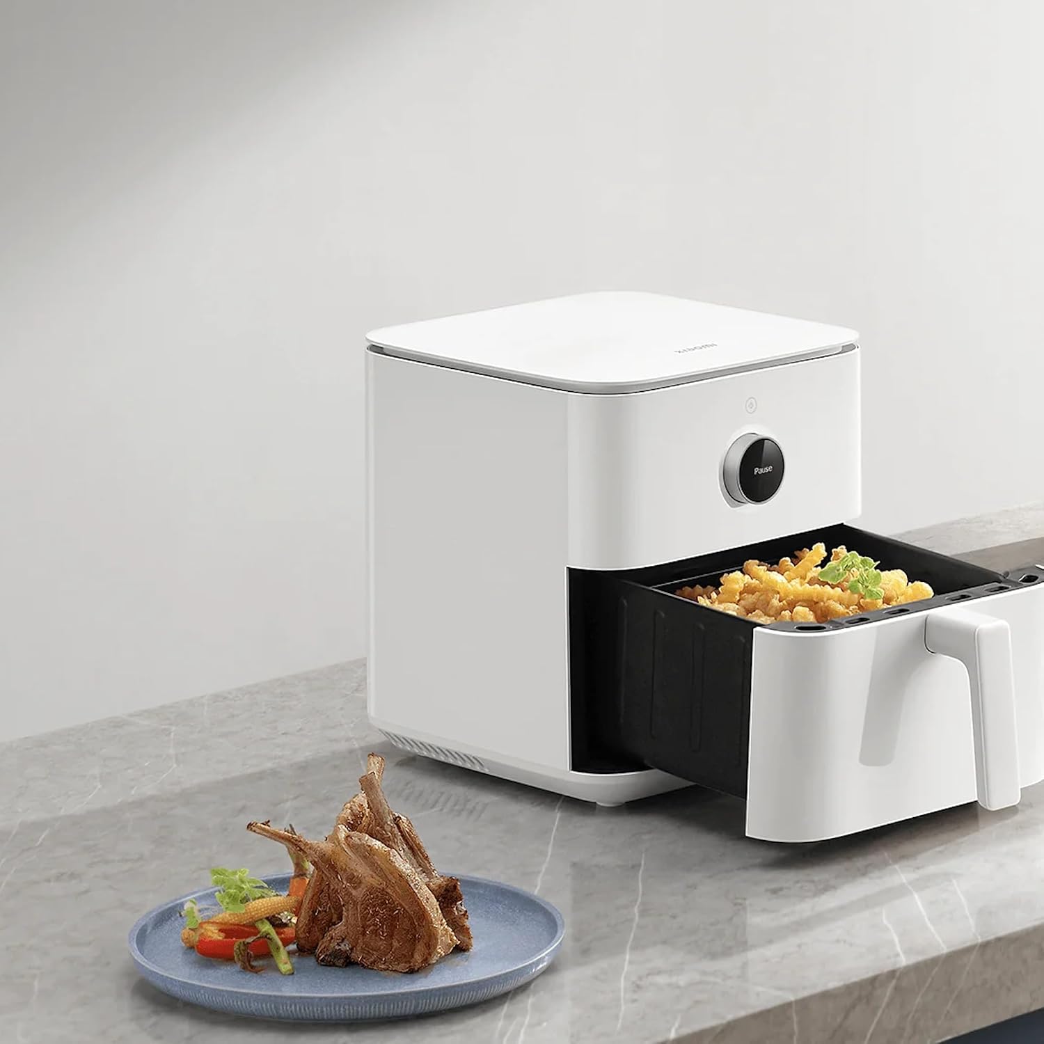 Xiaomi Smart Air Fryer Pro 4 L blanc posé sur un plan de travail en marbre, tiroir ouvert sur des frites dorées, à côté d'une assiette de côtelettes